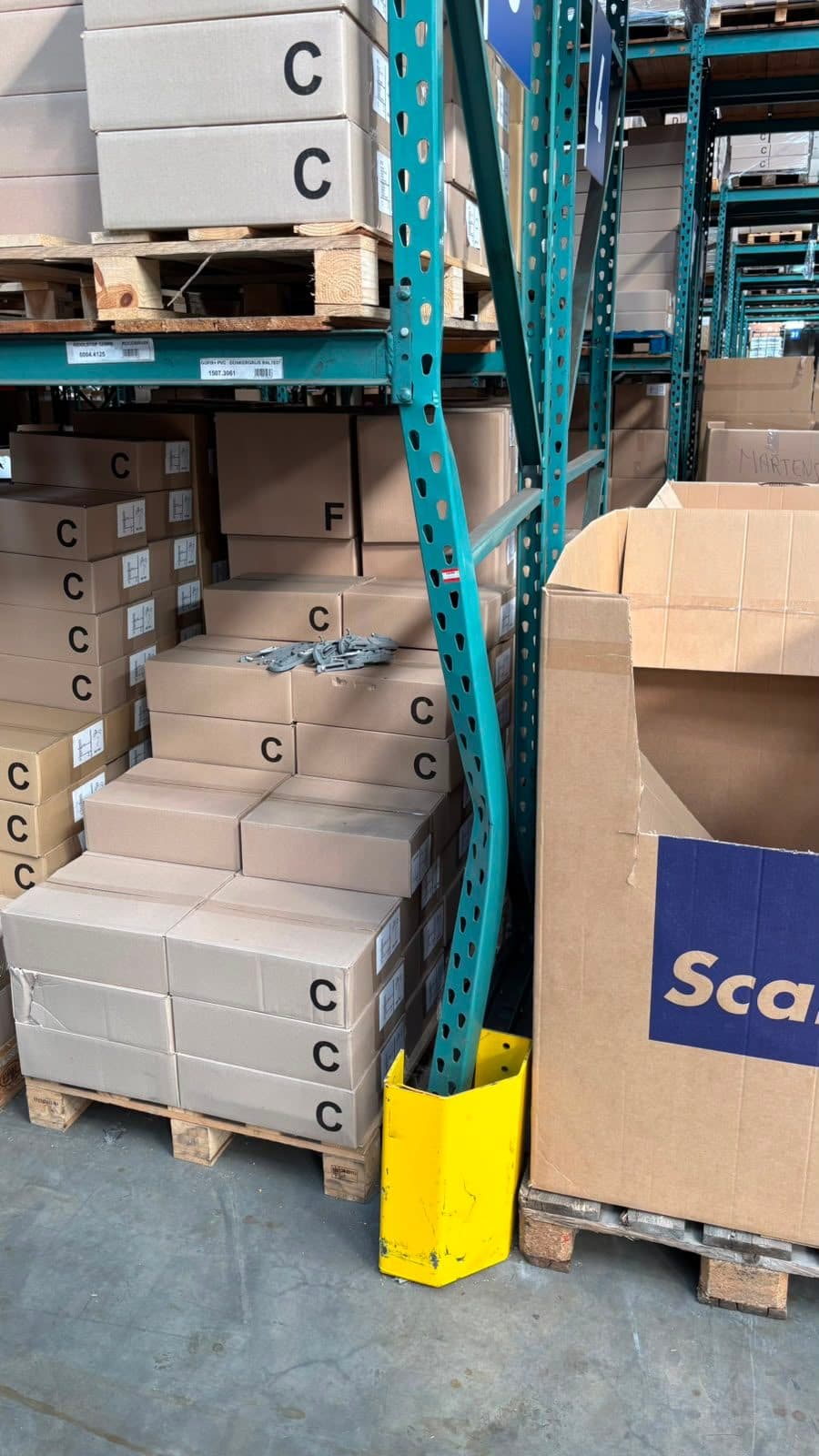Een aangereden, vervormde staander van een palletstelling met een beschadigde staanderbeschermer