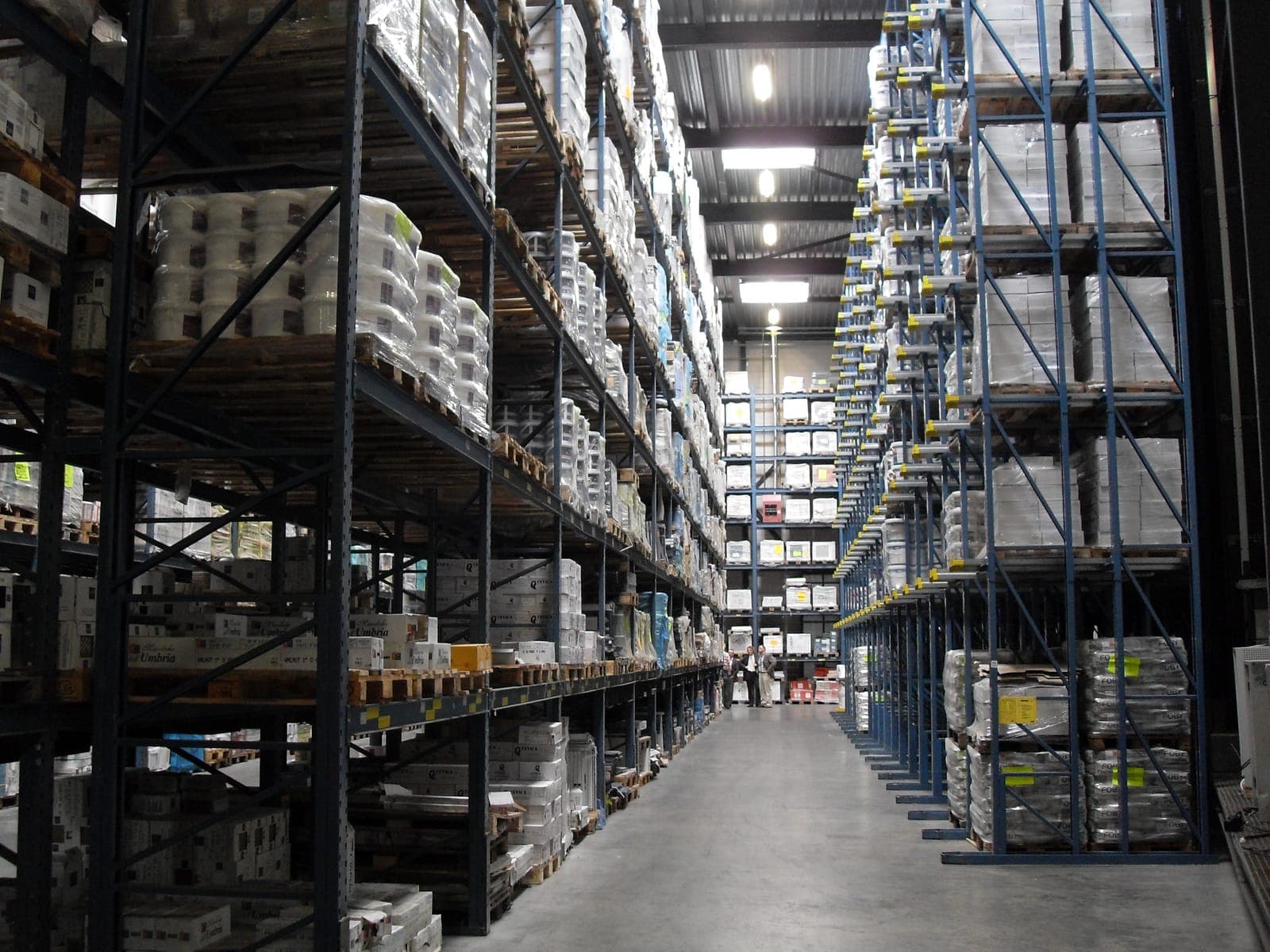 Hoge blauwe inrijstelling volledig gevuld met pallets in een magazijn