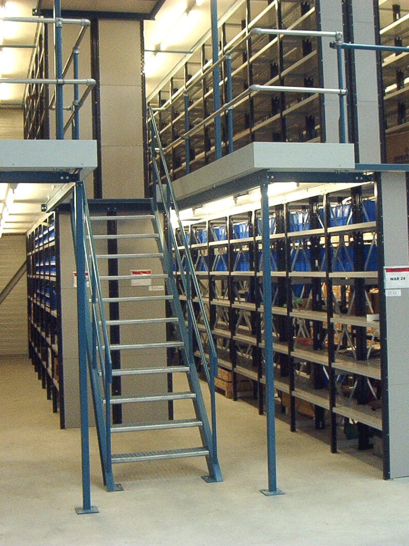 Bordes met legbordstellingen en een toegangstrap in een magazijn, onafhankelijk beoordeeld op veiligheid