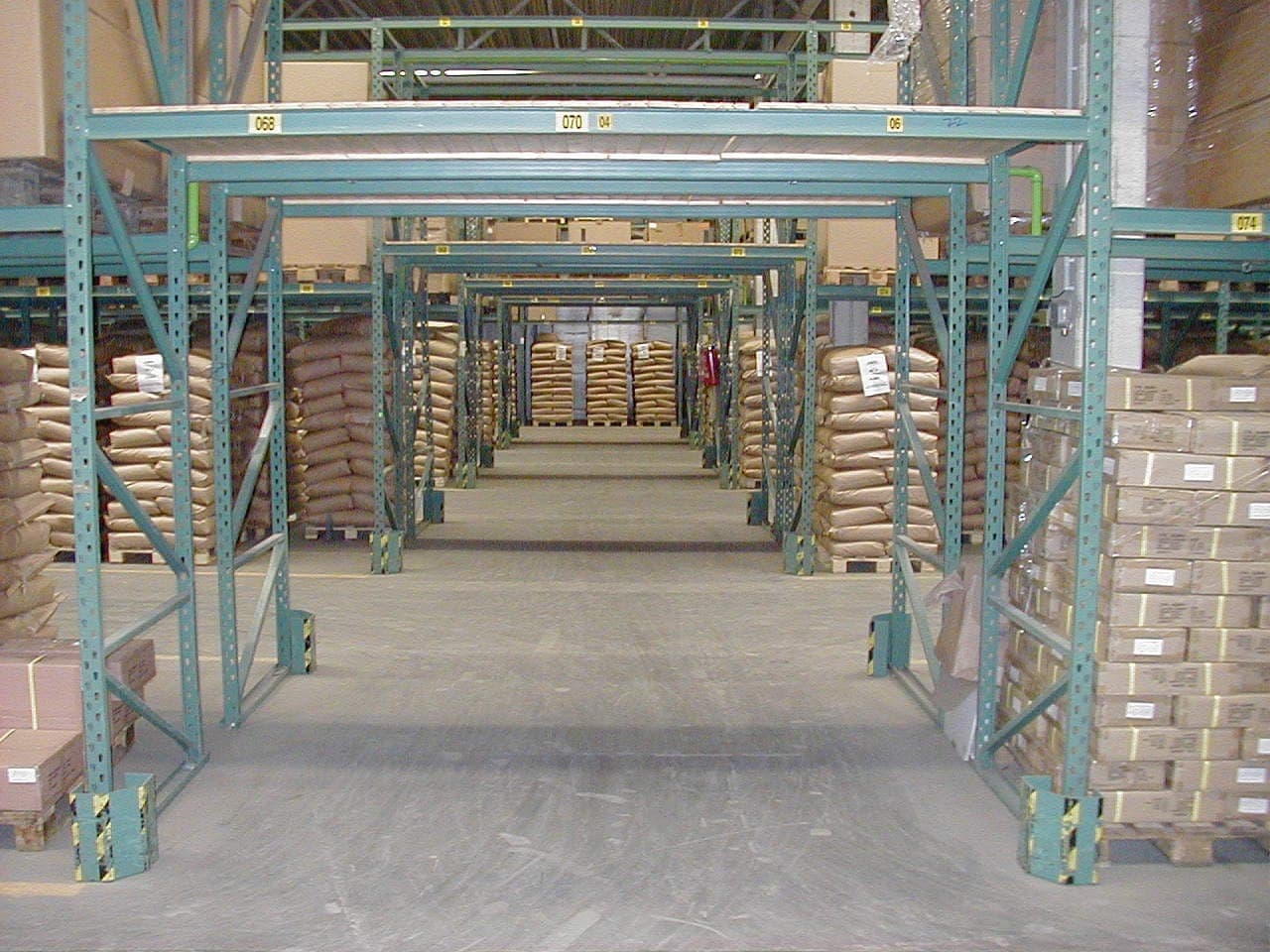 Gevulde palletstellingen met onderdoorgangen en gele aanrijdbeveiliging op de staanders